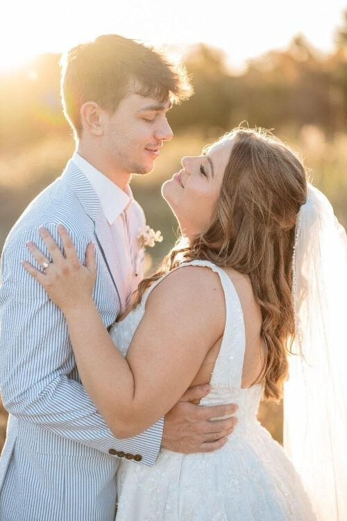 A couple in a wedding dress and suit embrace at golden hour in Hilton Head Island Beach while posing for wedding photos.